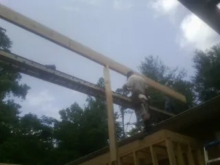 Carpenter setting a ridge beam over a new addition frame — Ice Dam Removal by Roofing Brothers in Port Saint Lucie