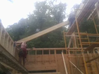 Carpenter raising a rafter beam on a new second story frame in Port Saint Lucie