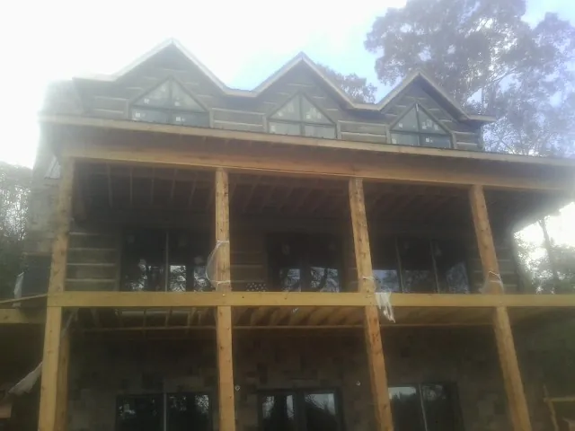 Dormers and porch framing on a large log home under construction — Roof Coating work by our crew in Port Saint Lucie