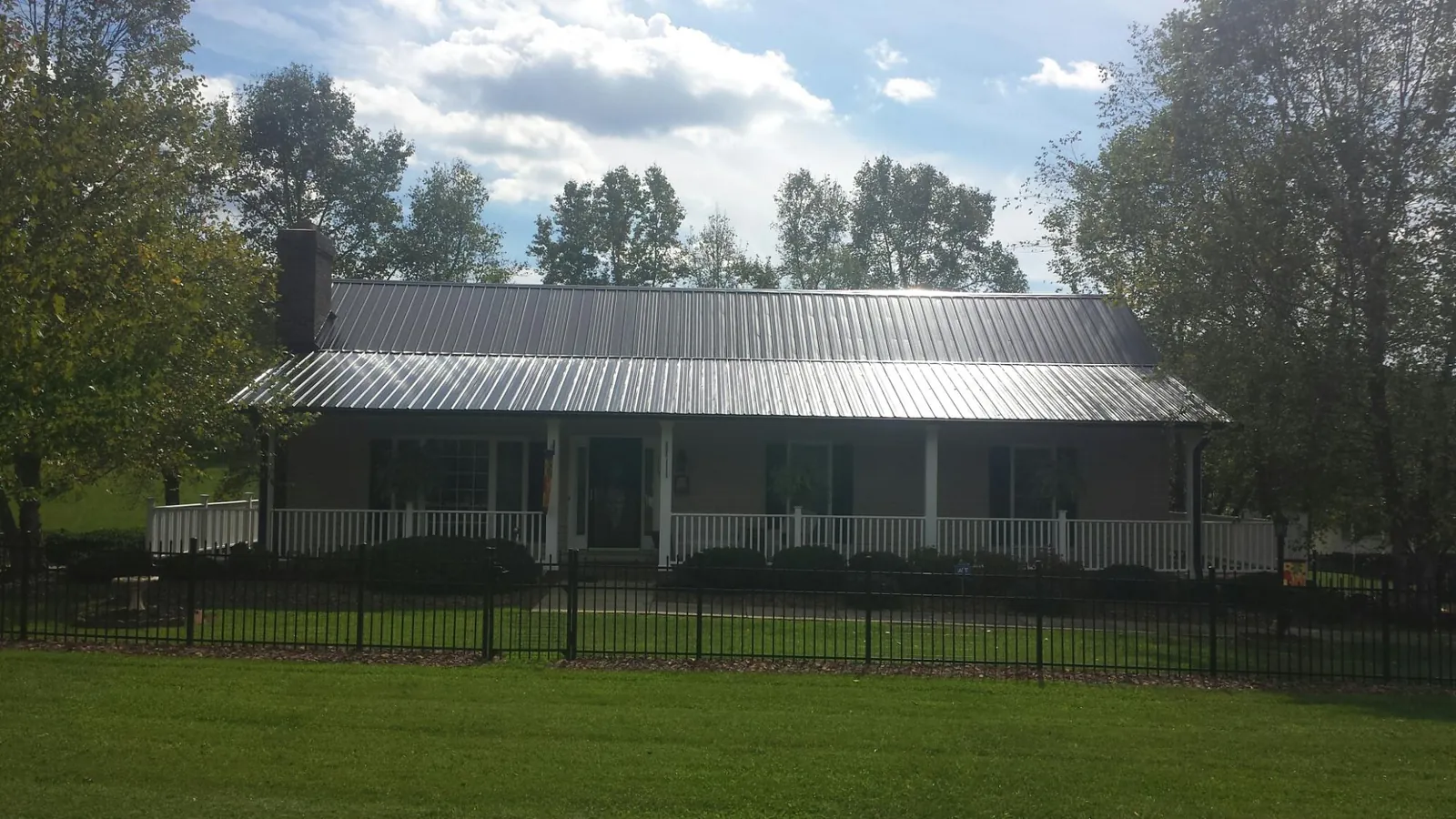 Gray metal roof on a brick ranch with a full width front porch — Gutter Guard Installation work by our crew in Port Saint Lucie